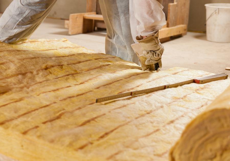 Handwerker schneidet eine Mineralwollmatte für die Dämmung zu